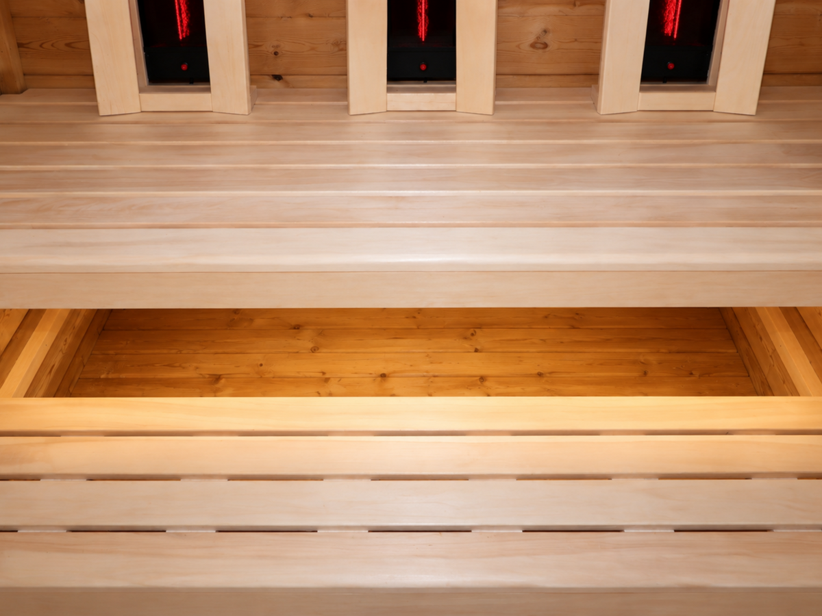 Houten banken op twee hoogtes met warme verlichting onder de bovenste bank in de Passion Sauna House Olivin 510.