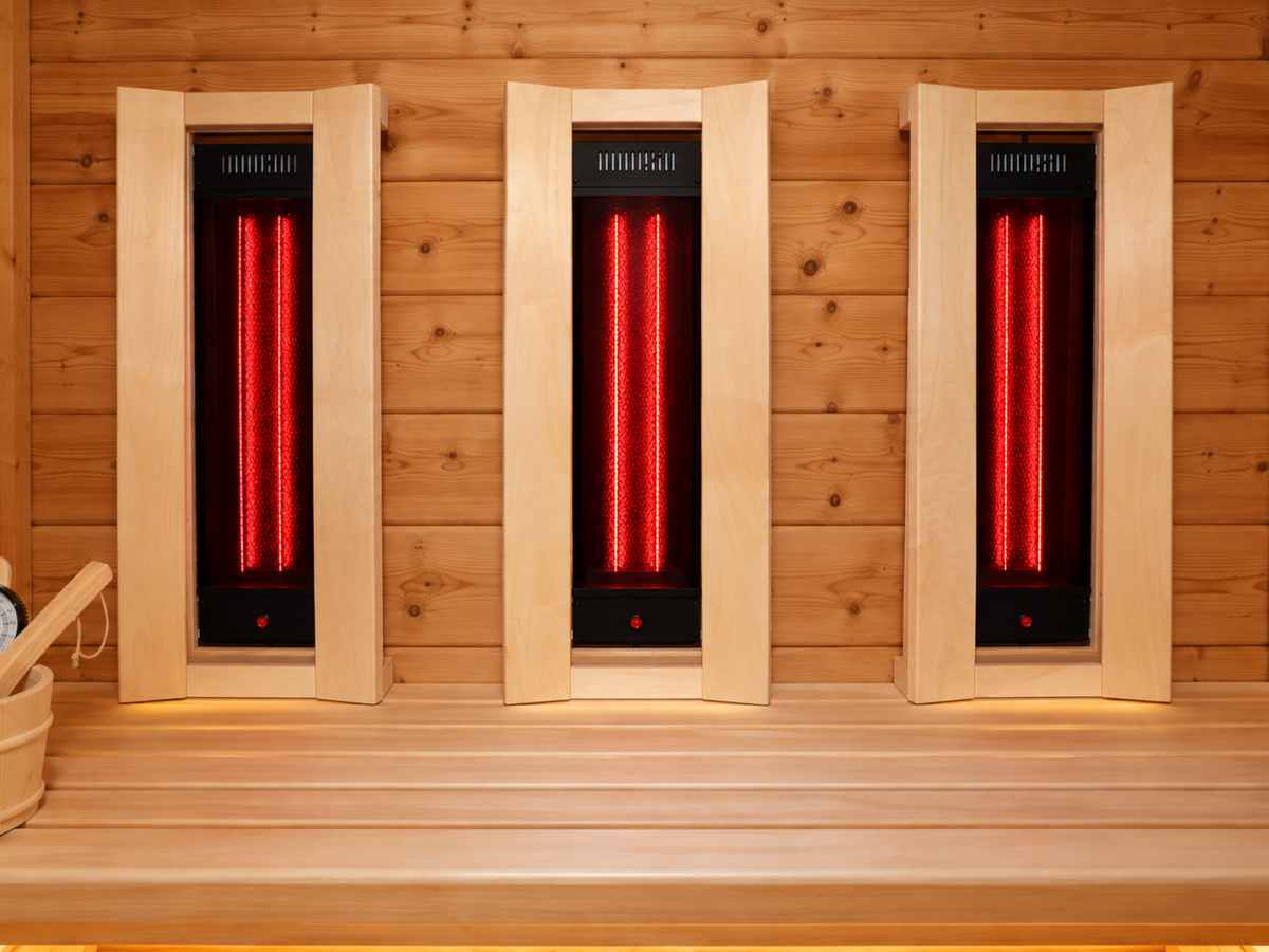 Drie rode infraroodstralers boven een houten saunabank in de Passion Sauna House Olivin 230.
