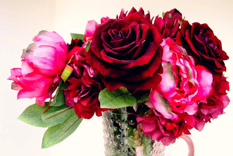 Boeket met donkerrode en roze bloemen in een vaas.