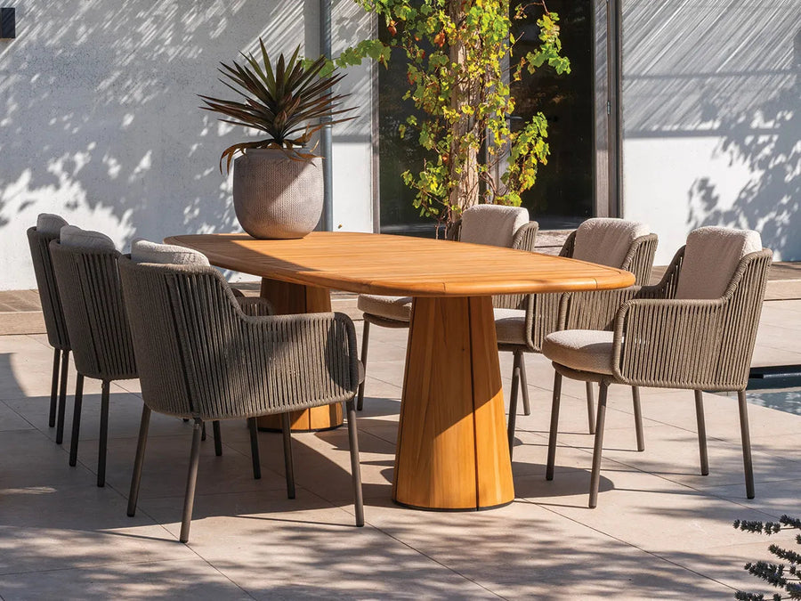 Houten tuintafel met donkere gestoffeerde stoelen op een terras.