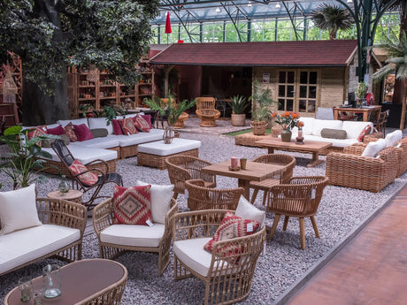 Tuinmeubelen met lichte kussens en ronde tafels voor een houten tuinhuis in de showroom.