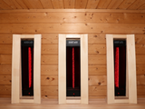 Drie rode infraroodstralers in houten omlijstingen boven de bank van de Passion Sauna House Olivin 510.