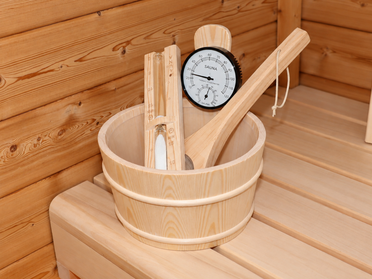 Houten opgietemmer met lepel, thermometer en zandloper op de bank van de Passion Sauna House Olivin 510.