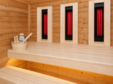 Houten bank met onderbankverlichting en drie rode infraroodstralers in de Passion Sauna House Olivin 230.