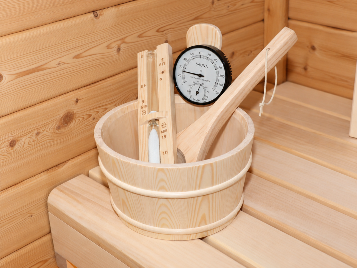 Houten opgietemmer met lepel, thermometer en zandloper op de bank van de Passion Sauna House Olivin 230.
